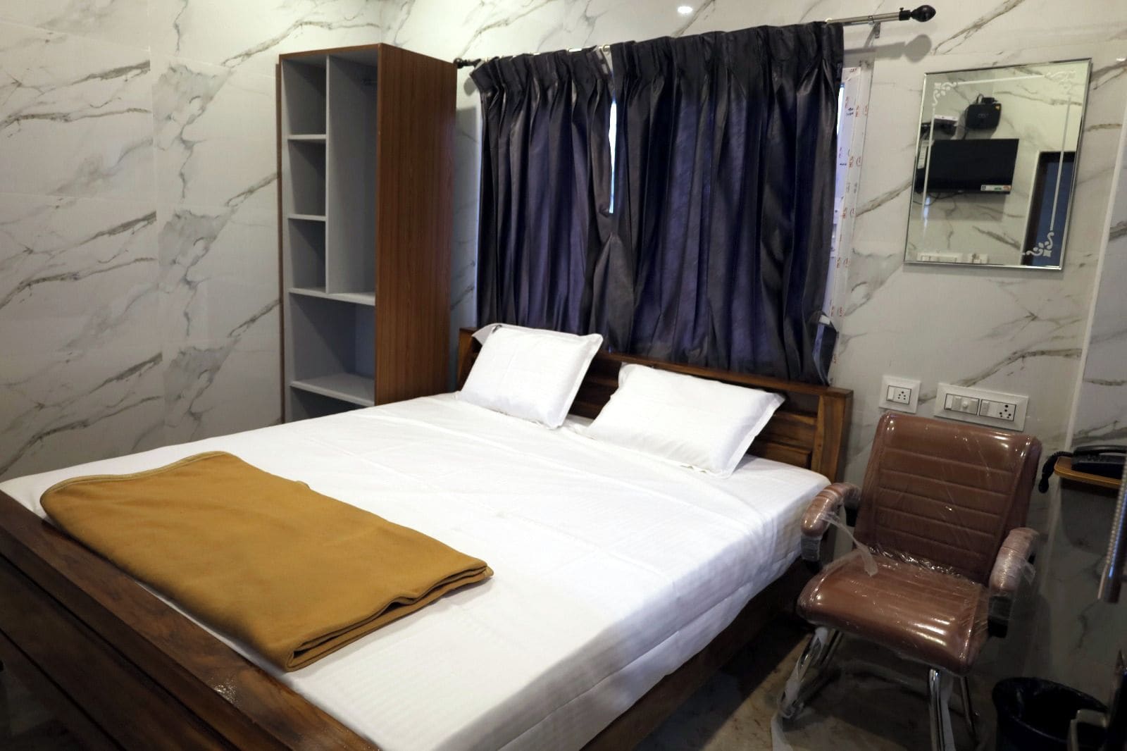 Una habitación de hotel con cama, armario de madera, zona de estar y un espejo en la pared.
