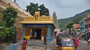 A temple with a traditional architectural style, a paved street, and a tuk-tuk parked in front. - Maruti residency (Tiruvannamalai)