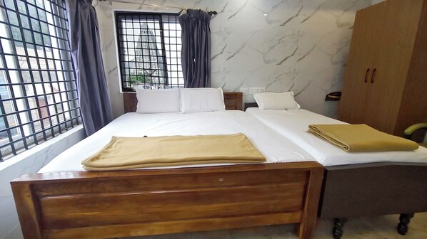 A hotel room with a wooden bed, white bedding, a window with metal bars, and a marble-patterned wall. - Maruti residency (Tiruvannamalai)