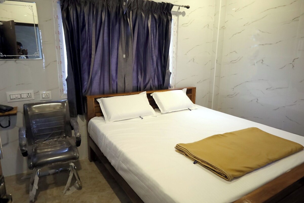 Una habitación de hotel con cama, una silla, un espejo y una ventana con cortinas.