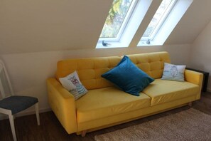 A yellow sofa with two pillows, a chair, and a skylight above. - Holiday home with 4 bedrooms (Osterhever)