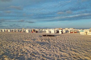 Una playa con filas de carpas blancas, cada una identificada con un número.