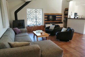 A living room with a sofa, armchairs, a coffee table, a TV, and a fireplace. - Holiday home in Provence (Merindol)
