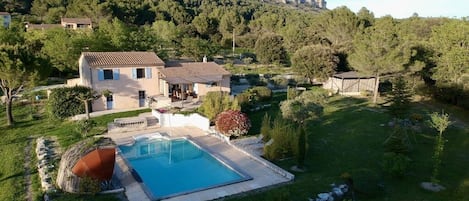 Una propiedad residencial con piscina, patio techado y montañas al fondo.