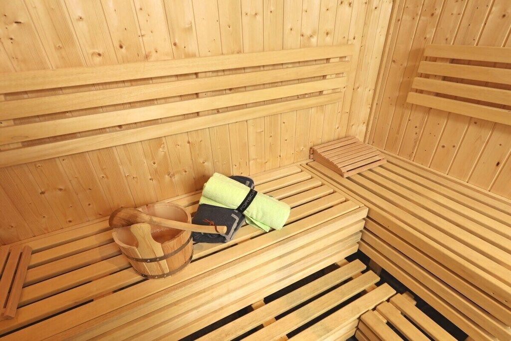 A sauna with wooden benches and a wooden bucket.
