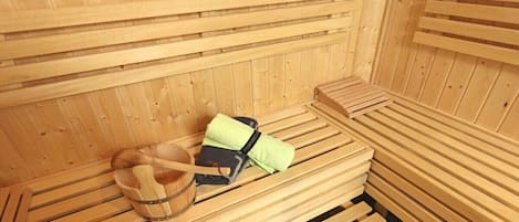 Una sauna con bancos de madera y un balde de madera.