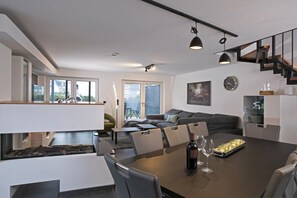 A modern dining area with a long table, chairs, and a wine bottle. - House Comfort by the lake (Göhren-Lebbin)
