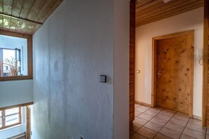A hallway with a wooden door, a light switch, and a window. - Holiday apartment with 2 bedrooms (Gaißach)