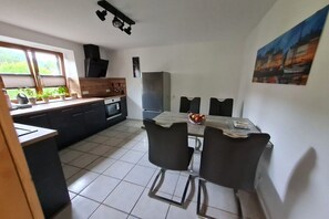 A compact kitchen with a dining area, a built-in oven, and a refrigerator. - Holiday apartment with 2 bedrooms (Gaißach)