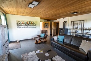 Ein Wohnzimmer mit einer Ledersofa, einem Ledersessel, einem Couchtisch und einem Gemälde an der Wand.