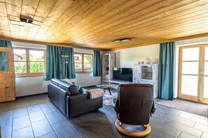 A living room with a sofa, a chair, a television, and a fireplace. - Holiday apartment with 2 bedrooms (Gaißach)