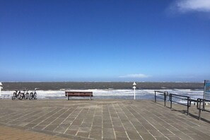 A paved walkway with a bench and bicycles, overlooking a stormy sea. - Holiday apartment with 1 bedroom (Norderney)