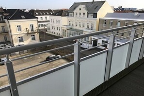 A hotel with a balcony overlooking a parking area and other buildings. - Holiday apartment with 1 bedroom (Norderney)