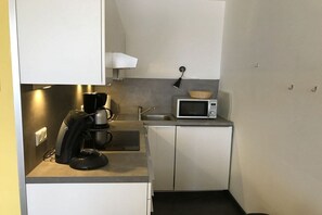 A compact kitchenette with a coffee maker, microwave, and a small sink. - Holiday apartment with 1 bedroom (Norderney)