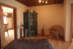 A room with a wooden ceiling, a green cabinet, a wicker chair, and a dark rug. - Holiday apartment with 3 bedrooms (Hallgarten)