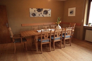 A dining area with a wooden table and chairs, a vase with flowers, and artwork on the walls. - Holiday apartment with 3 bedrooms (Hallgarten)