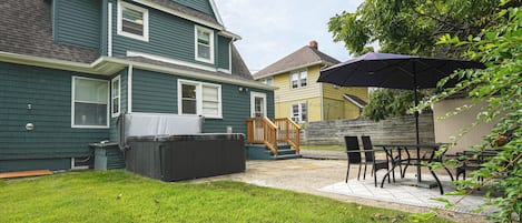 A residential backyard with a covered hot tub, a wooden deck, and outdoor furniture.