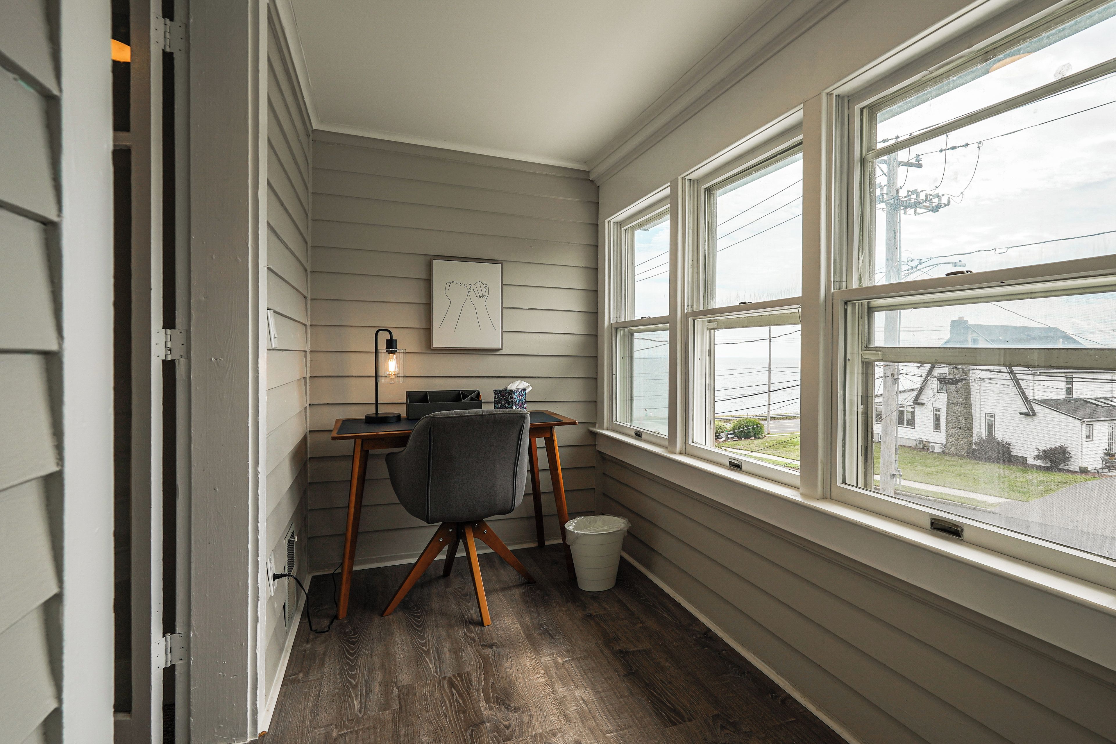 A corner room with a desk, chair, and a window overlooking a residential area.