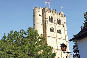 A castle-like building with a tower, arched windows, and a flag on top. - Apartment in Eifel with 0 bedrooms (Münstermaifeld)