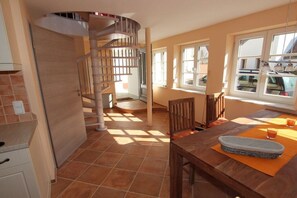 A kitchen with a spiral staircase, a dining table with a placemat, and a window with a view of the outside. - Holiday apartment with 2 bedrooms (Bamberg)