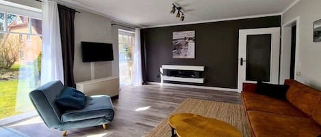 A living room with a sofa, a coffee table, a flat-screen TV, and a fireplace.