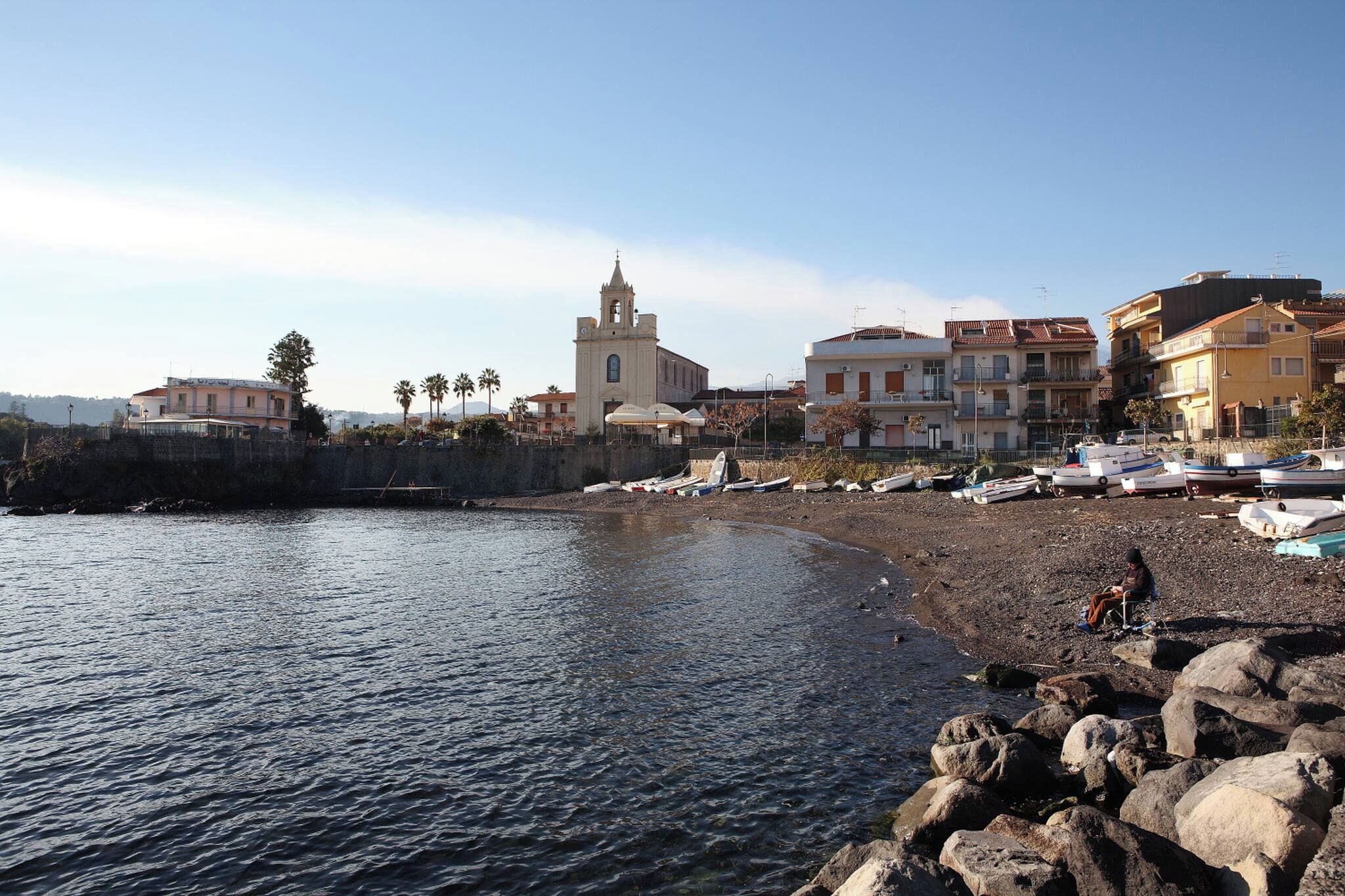 Eine Küstenstadt mit Kirche, felsigem Strand und Booten.
