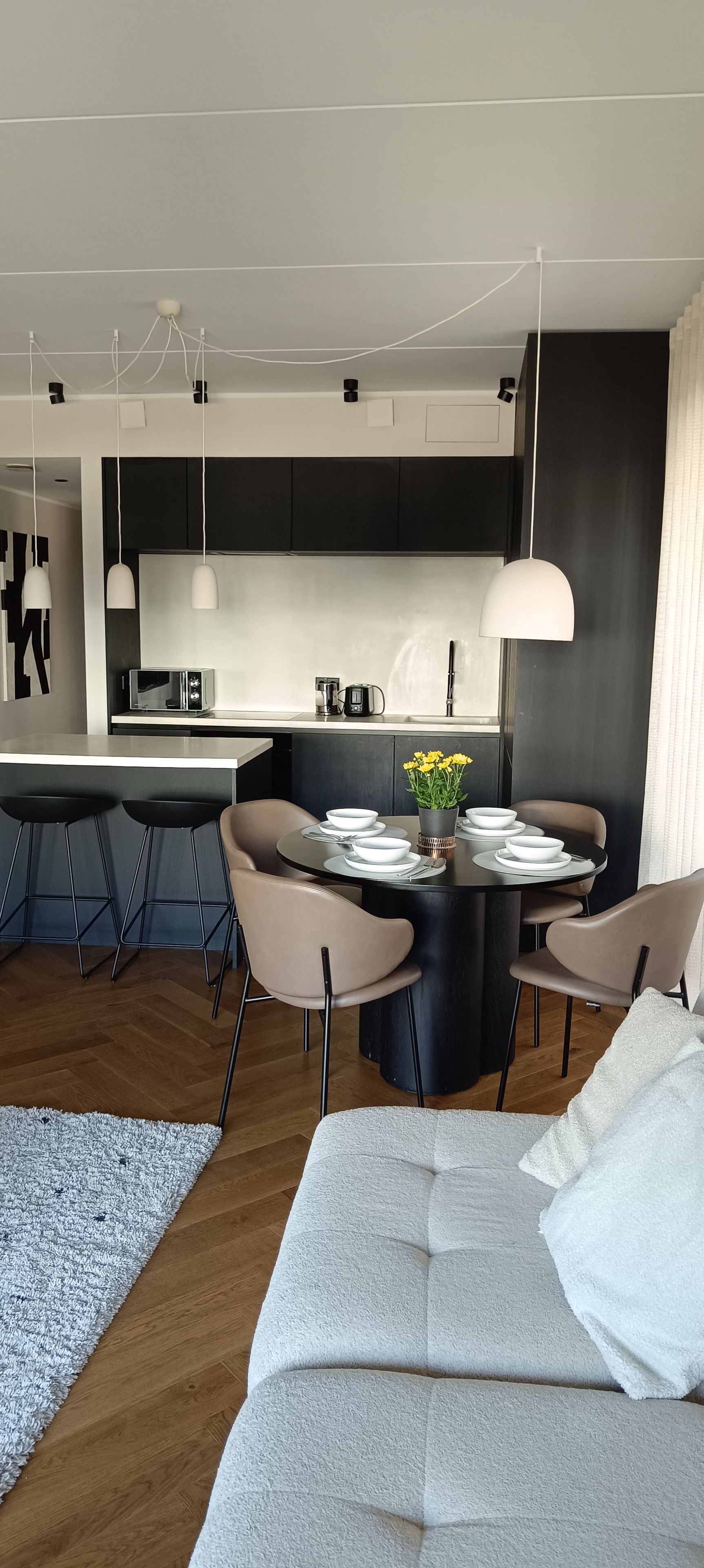 A modern kitchen with a central island, bar stools, and pendant lighting.