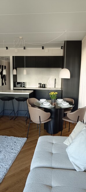 A modern kitchen with a central island, bar stools, and pendant lighting. - Kalaranna family & business (Tallinn)