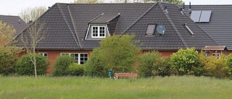 A residential building with a sloped roof, a small window, and solar panels.