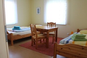 A room with two single beds, a wooden table with chairs, and a red rug. - House Swallow's Nest (Nordstrand)