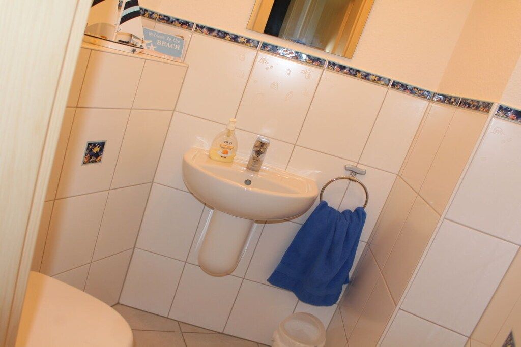 Un baño con lavamanos, inodoro y una toalla azul colgada en la pared.