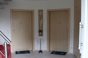 A hotel entrance with two wooden doors, a vertical sign with an anchor, a small plant, and a metal stand. - House Swallow's Nest (Nordstrand)