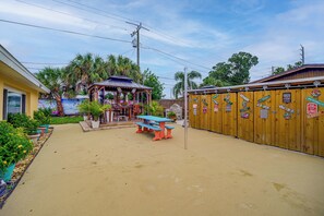 A covered outdoor seating area with a table and chairs, surrounded by a wooden fence with various signs. - 'Trop Rock Inn' Outdoor Oasis & Music Studio (Melbourne)