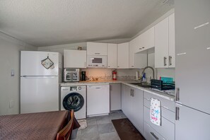 A compact kitchen with a refrigerator, microwave, oven, and dishwasher. - 'Trop Rock Inn' Outdoor Oasis & Music Studio (Melbourne)
