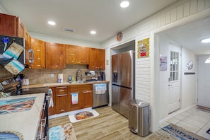 A kitchen with wooden cabinets, a stainless steel refrigerator, and a coffee machine. - 'Trop Rock Inn' Outdoor Oasis & Music Studio (Melbourne)