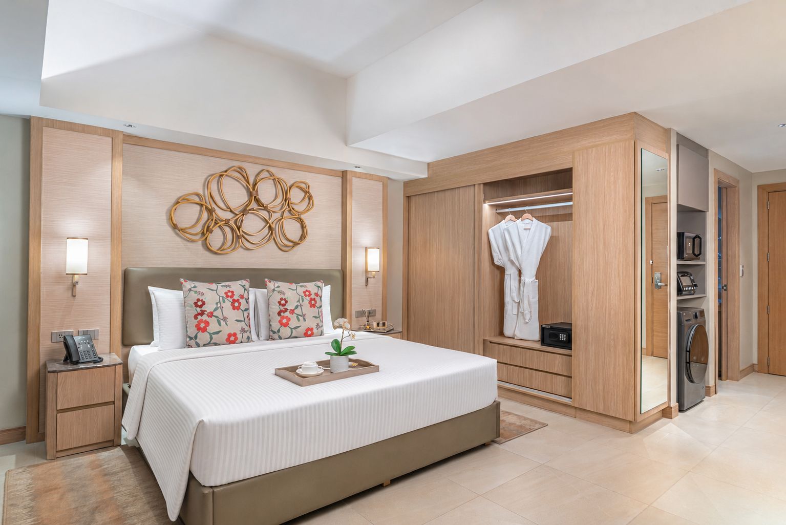 Una habitació d'hotel moderna amb un llit gran, una taula de nit amb un telèfon, una làmpada de paret i un armari encastat amb mirall.