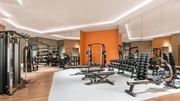 A modern gym with various exercise equipment, including weight machines, free weights, and a bench.