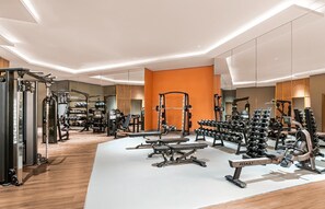 Un gimnasio moderno con diferentes máquinas de ejercicio, pesas y un banco.