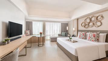 A hotel room with a bed, a desk, a TV, a round table, and a window with curtains.