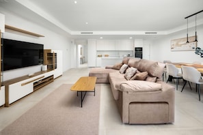 Un salon moderne avec un canapé d’angle, une table basse et un téléviseur.