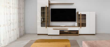 A living room with a flat-screen TV, wooden entertainment unit, and a coffee table.