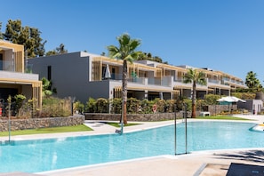 Un hôtel moderne doté d’une piscine, de nombreux balcons et d’un aménagement paysager luxuriant.