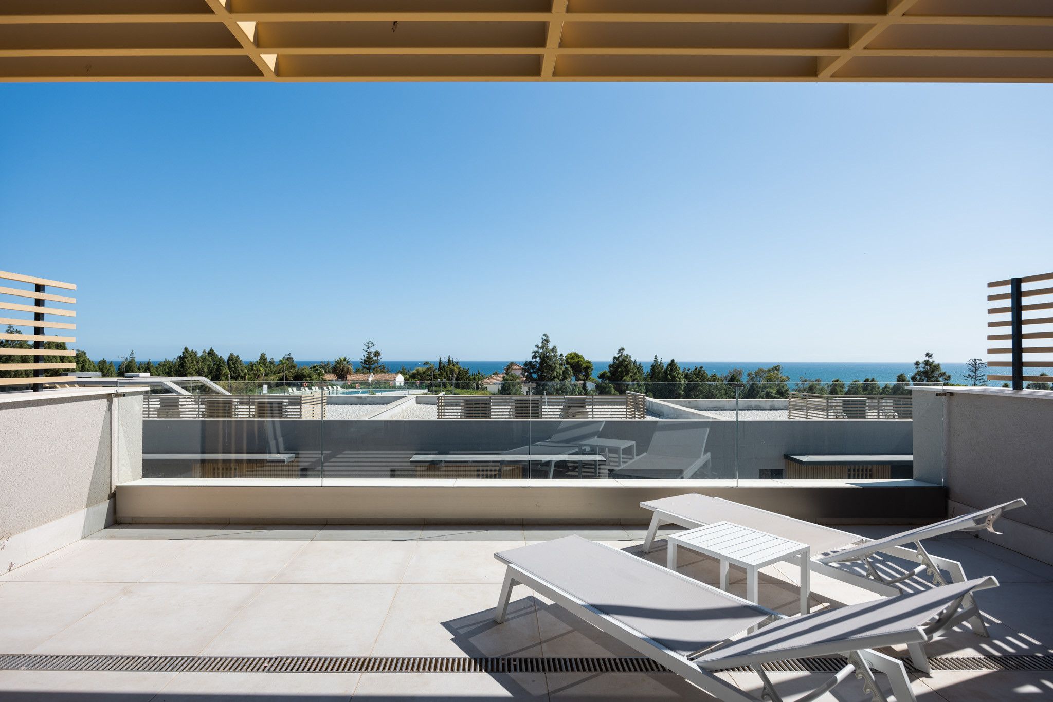 A rooftop terrace with sun loungers and a pool view.