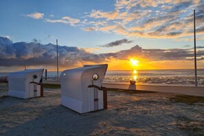 Two beach chairs on a sandy beach with a sunset in the background. - Windloper (Wallbox!) (Norden)
