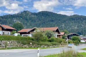 Ein Wohngebiet mit Häusern mit geneigten Dächern, einer Steinmauer und einem Berg im Hintergrund.