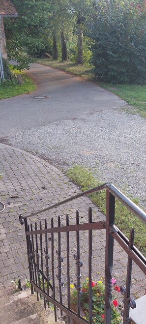 A paved driveway leading to a house with a metal fence in the foreground.