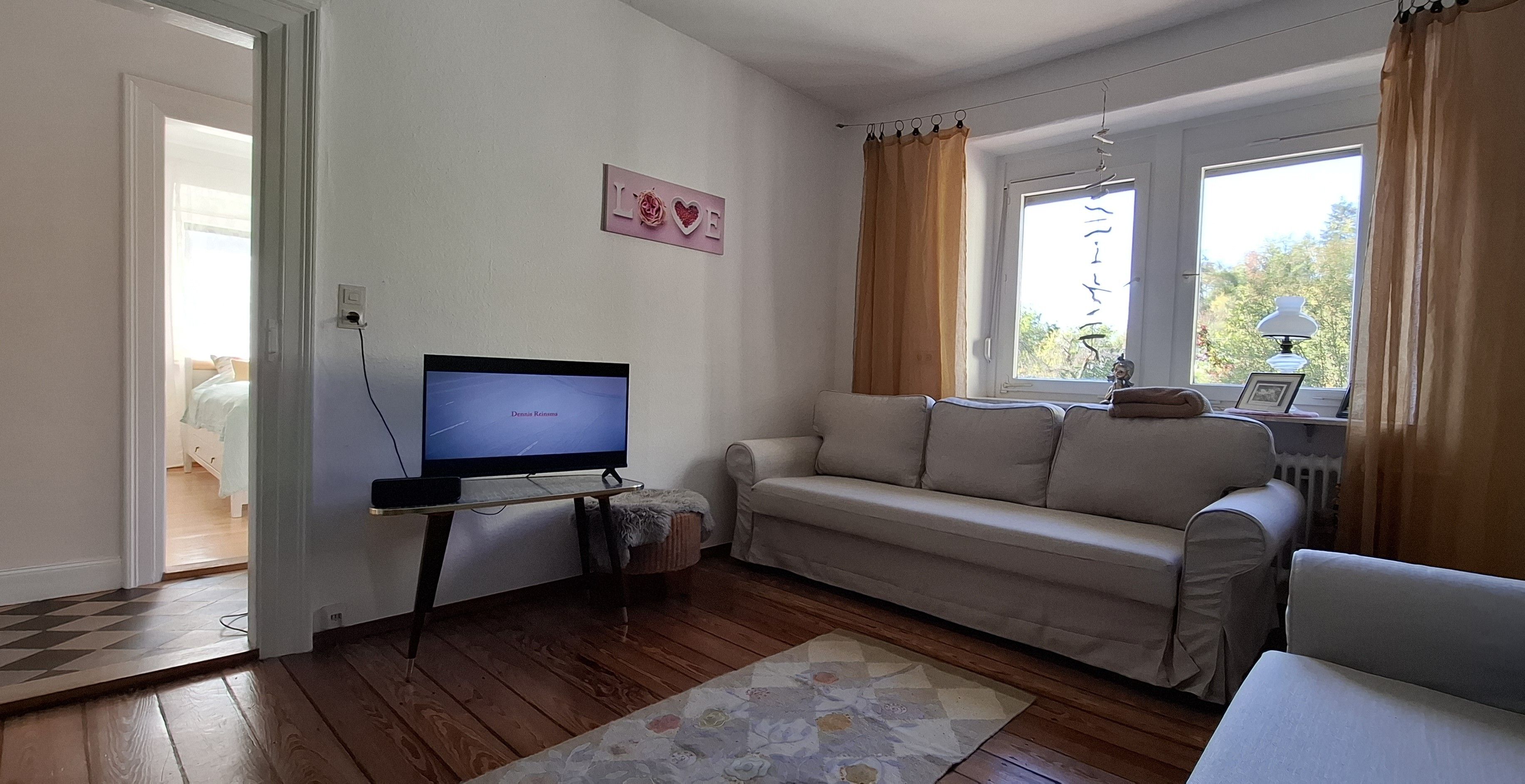 Un salon avec une télévision, un canapé et un tapis.