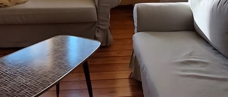 Una habitación con sofá, una mesita y una ventana con cortinas.