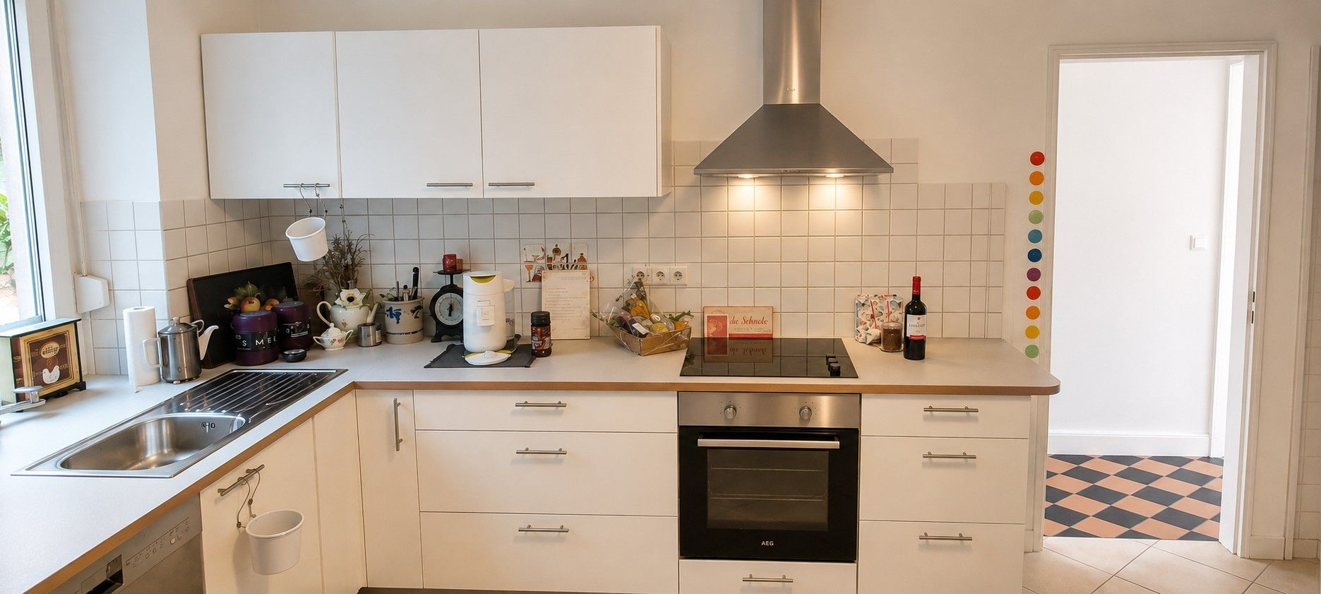 A modern kitchen with white cabinets, a stainless steel sink, and an oven.