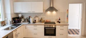 Una cocina moderna con armarios blancos, un lavamanos de acero inoxidable y un horno.